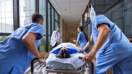 Healthcare workers rushing a patient in a gurney to the emergency room 