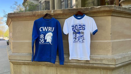 Photo showing two limited-edition Hudson Relays merch items—a t-shirt and a sweatshirt—hanging from the portico at Adelbert Hall