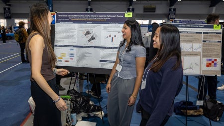 Photo of students presenting a poster at Intersections in fall 2025