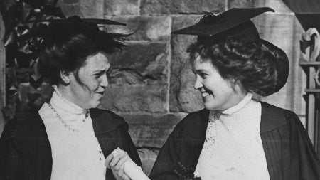 A black and white photo of two women wearing academic robes