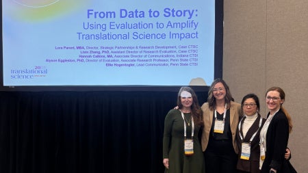 Four women standing in front of a presentation screen