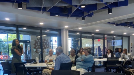 Woman standing and leading a discussion in a room with a group of seated people