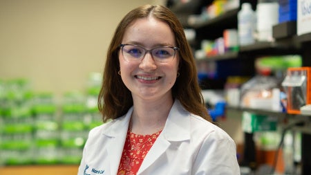 Photo of Chloe Meyer wearing a white coat in a lab setting