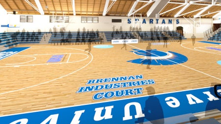 Interior of a gymnasium featuring a basketball court labeled "Brennan Industries Court" with blue and white bleachers and "Spartans" on the wall.