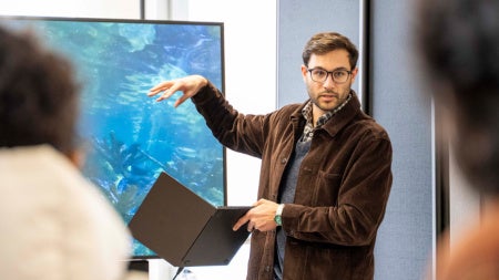 Zach Patterson presents to an audience, gesturing towards a screen.