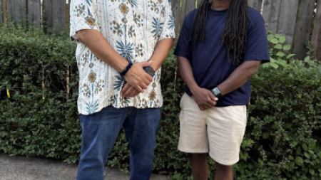 Juan Silva stands with a friend on a driveway.