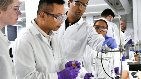 Team of researchers looking through microscope