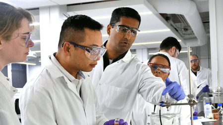 Team of researchers looking through microscope