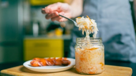 Close-up of a fork with sauerkraut and a piece of Bavarian sausage 