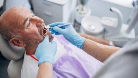 Photo of man being examined in a dental chair.