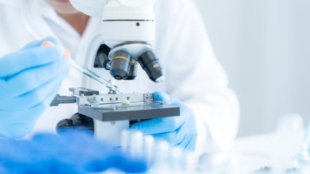 Photo of a medical researcher using a high-powered microscope.