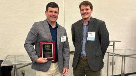 Christopher Wirth takes a group photo holding L.E. Scriven Young Investigator Award statue