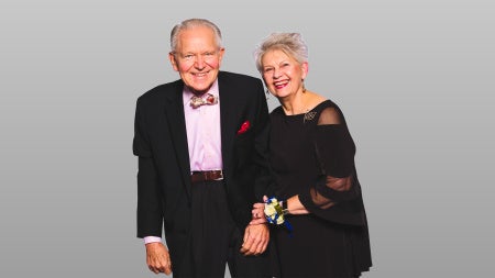 Man and woman holding hands smiling with a grey background