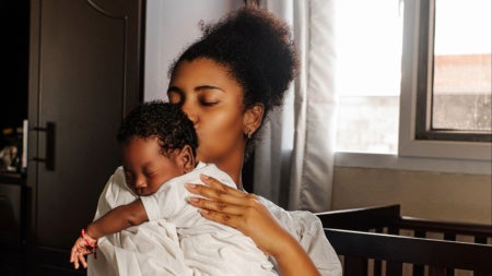 A mother holds a small baby wearing white
