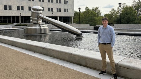 Noah Perrin standing in front of a sculpture of a gavel at the Thomas J. Moyer Ohio Judicial Center in Columbus