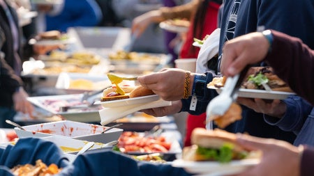 Close up photo showing people serving themselves at a campus buffet at an event