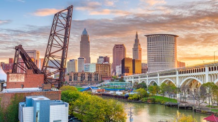 Photo of the Cuyahoga River with the Cleveland skyline in the background during a sunrise on a fall day
