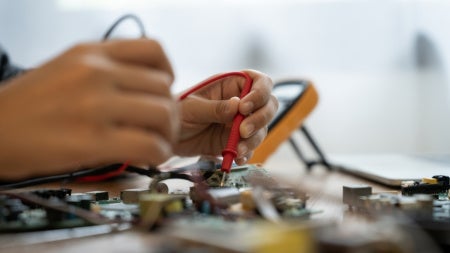 Close up of an unidentified person working on a computer circuit. 