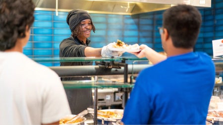 two students being handed food by a worker in Fribley Commons
