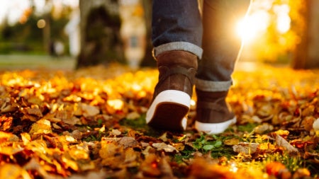 Close up of an unidentified person walking on autumn leaves