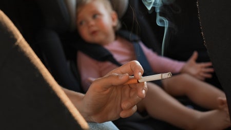 Image of a human smoking next to a baby