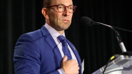 Luis Tollinche standing at a podium with his hand on his chest