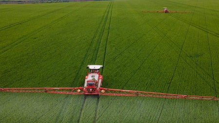 A crop sprayer moves through a field of greens