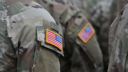 Close up of unidentified individuals wearing military uniform with an American flag patch