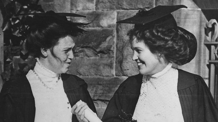 A black and white photo of two women wearing academic robes