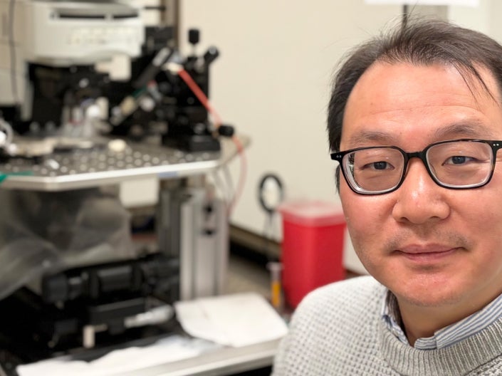A scientist sits next to a patch clamp electrophysiology setup