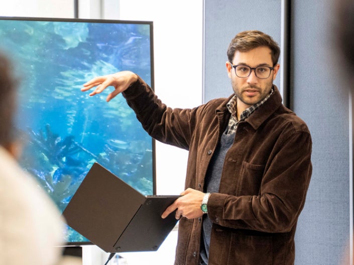Zach Patterson presents to an audience, gesturing towards a screen.