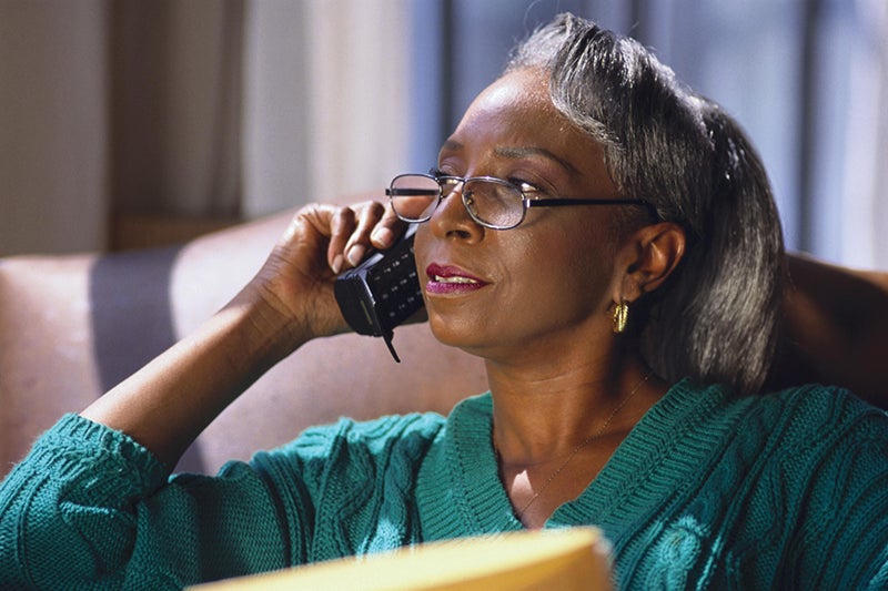 A women using the phone talking to a distance caregiver