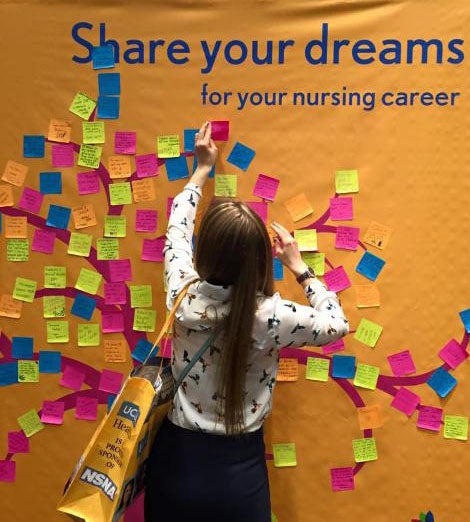 Picture of a new FPB student adding her wishes to a "share your dreams" poster