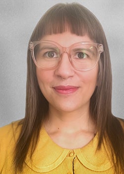 Headshot of woman in yellow shirt and clear glasses