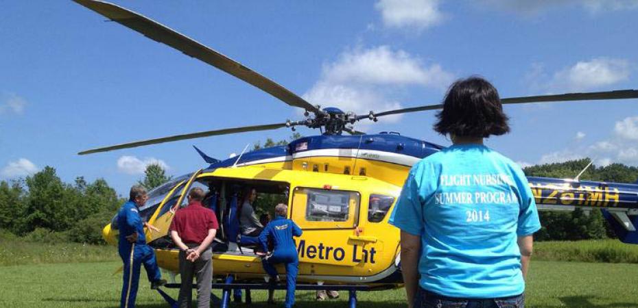 Picture of a student looking at a helicopter in a field.