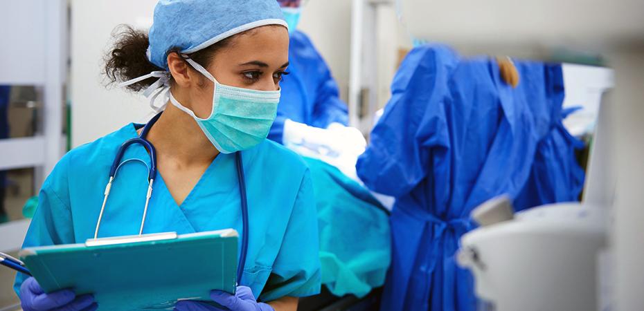 Nurse anesthetist in scrubs monitoring a patient.