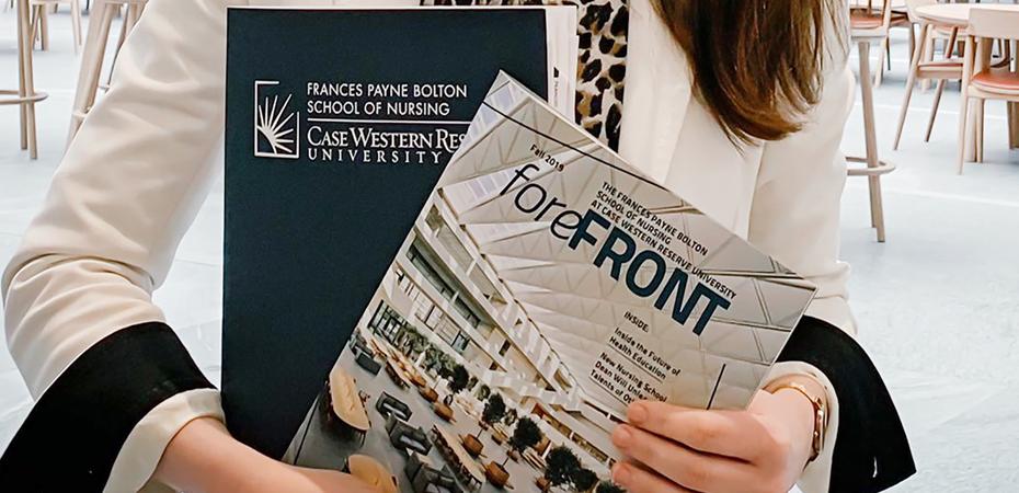 Female torso featuring hands holding the Forefront Magazine and an FPB Folder