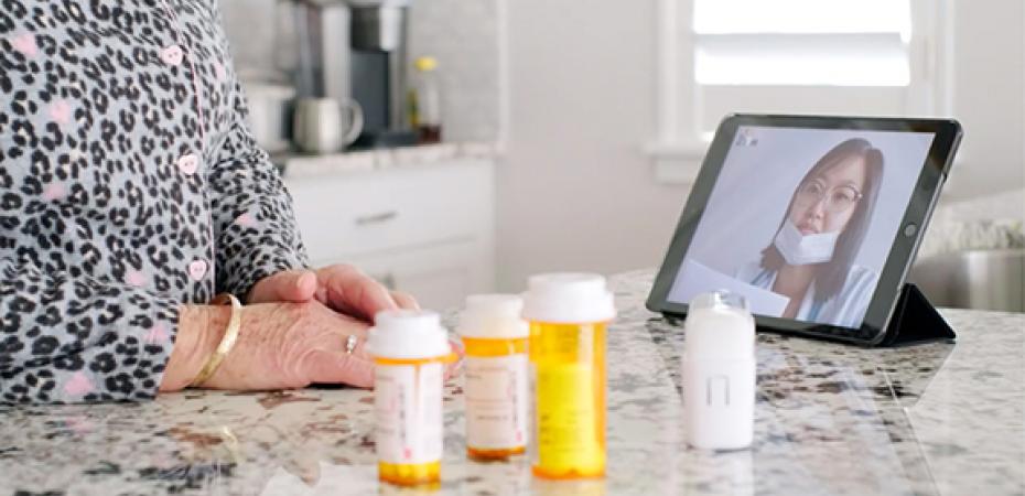 Patient talking to healthcare provider on a tablet with prescription bottles in front of them.