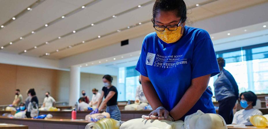 A nursing student performs CPR on a mannequin inside the classroom
