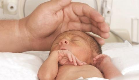 Picture of a NICU baby being comforted.