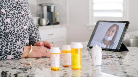 Patient talking to healthcare provider on a tablet with prescription bottles in front of them.
