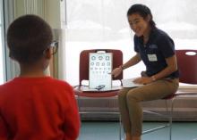 Photo of a teacher giving a young student a eye exam