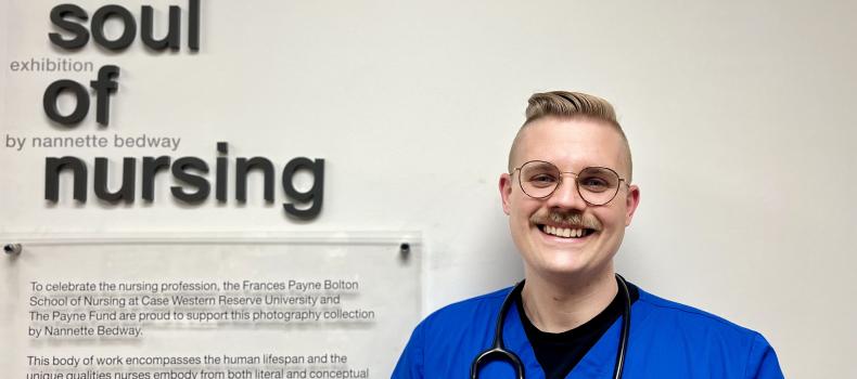 Young man in blue scrubs smiles at nursing school