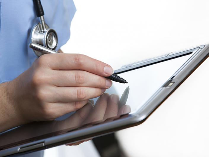 Stock photo of a doctor writing on a tablet.