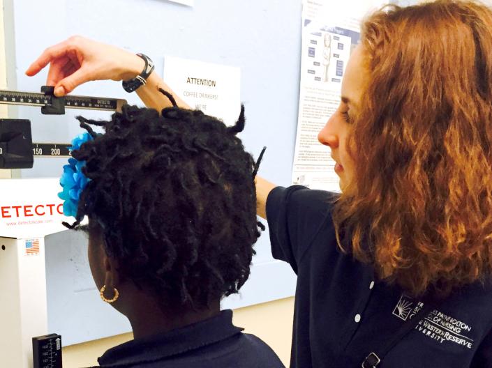 Jessica Chalas helping the school nurse at Tremont Montessori School collect heights and weights of first graders.