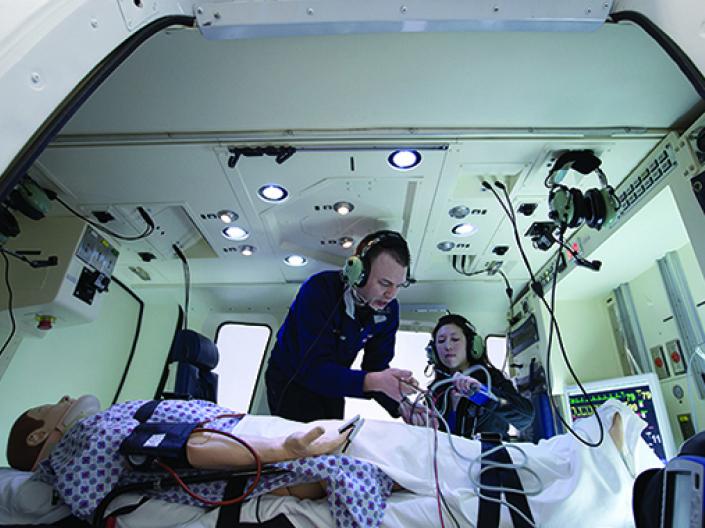 Picture of two students working on a dummy patient during a flight simulation exercise.