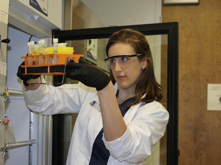 Picture of Sarah Givens inspecting speciemens in a lab.