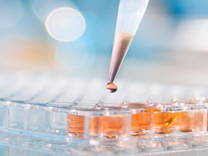 Dropper/pipette with liquid hovering over test tubes