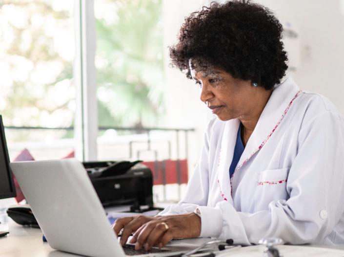 Woman wearing a white lab coat at a computer.