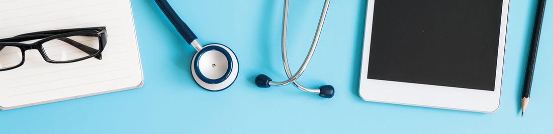 Stock photo of a pair of glasses, stethoscope, and tablet against a blue background.